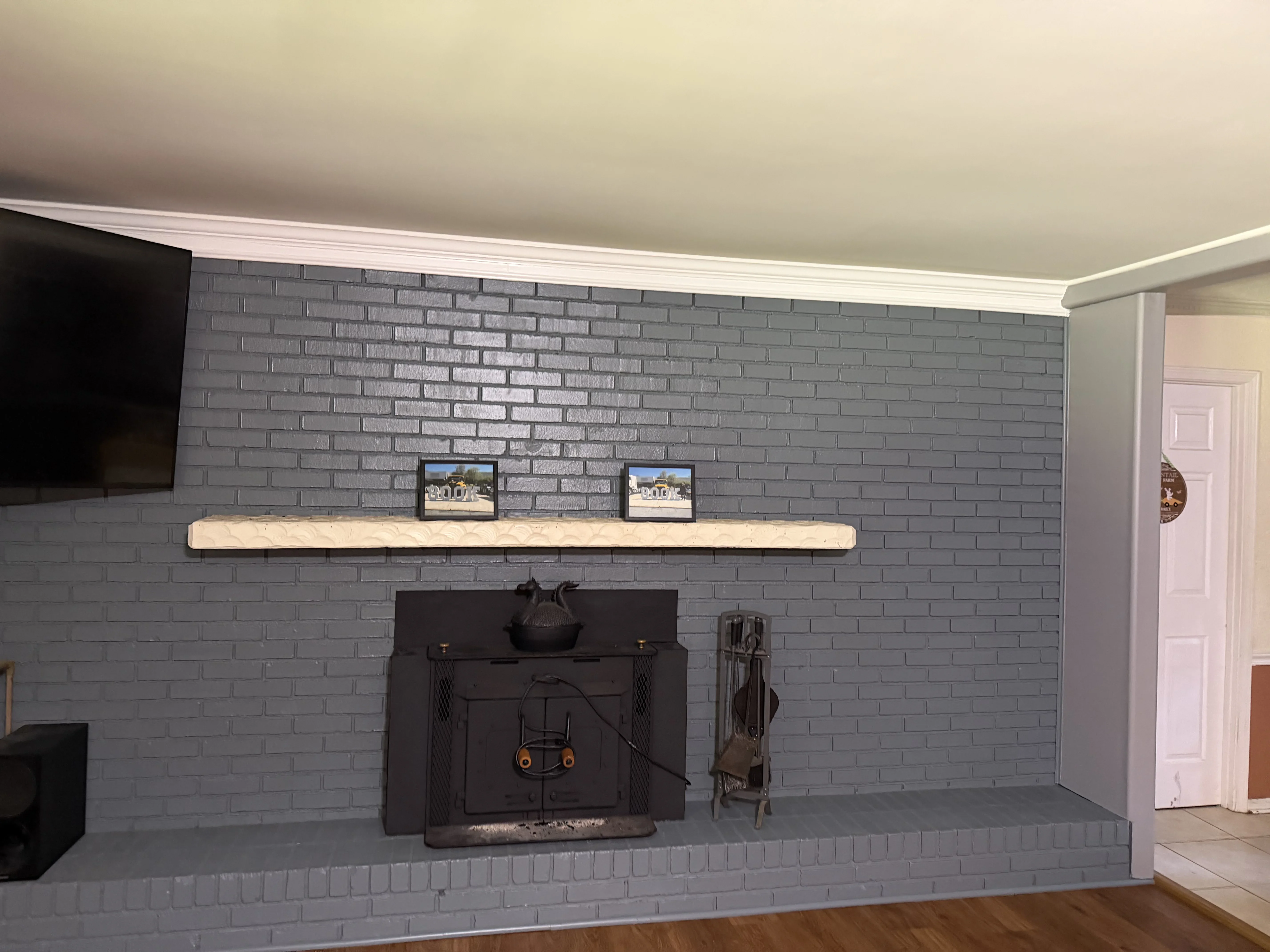 Gray painted brick fireplace with white mantel, black insert, and white trim molding