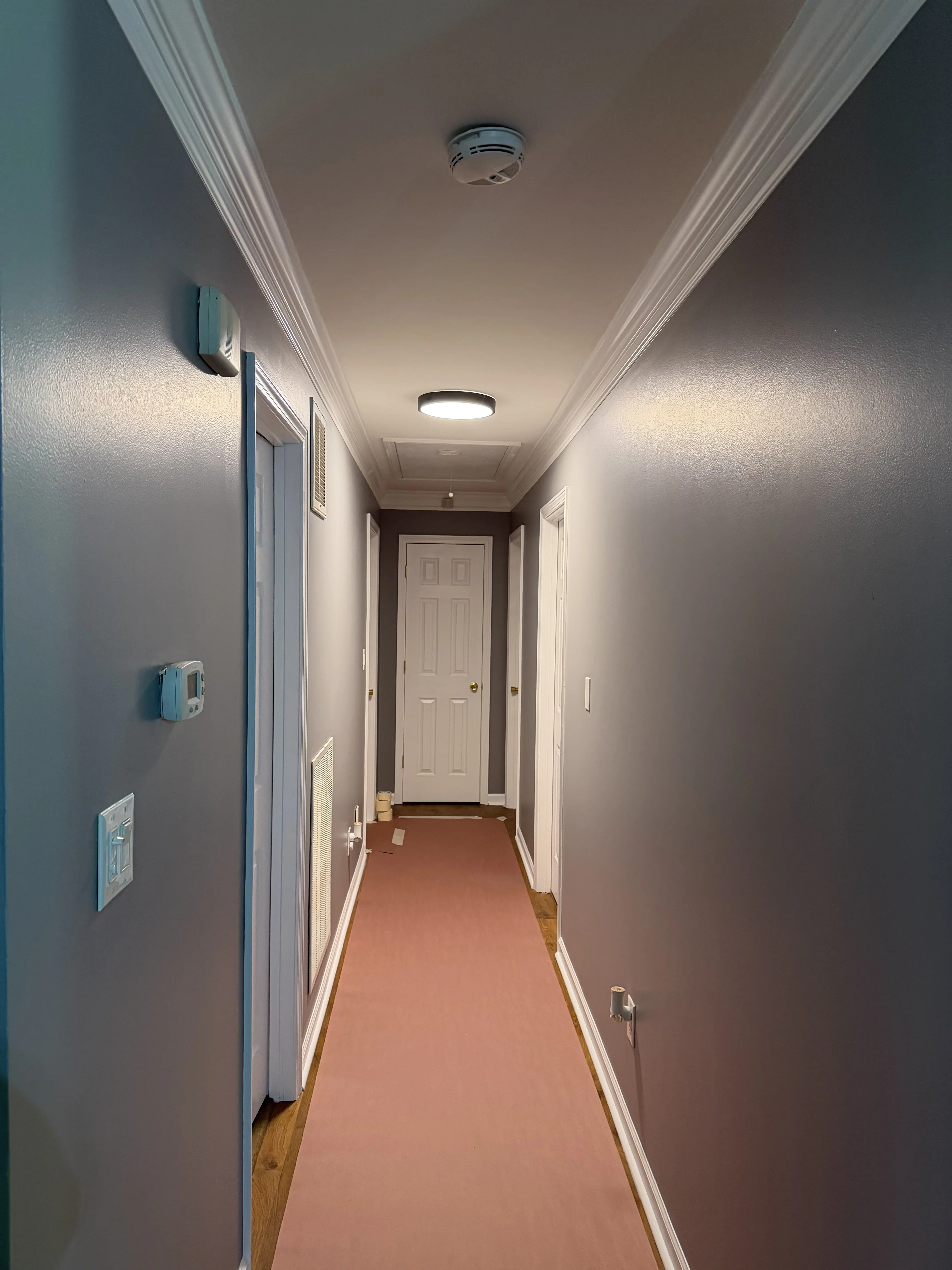 Hallway with gray painted walls, white trim, crown molding, and recessed lighting