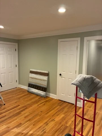 Sage accent walls with crisp white doors, trim, and recessed lighting in a Charlotte interior
