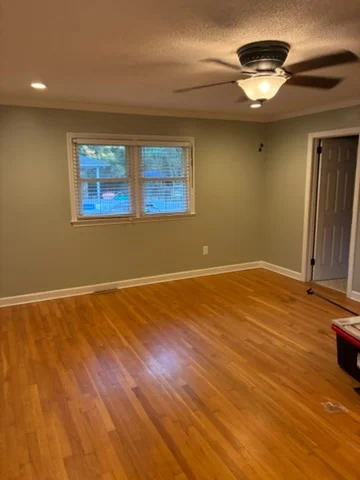 Sage-green Charlotte room with white baseboards, recessed lights, and a ceiling fan after painting