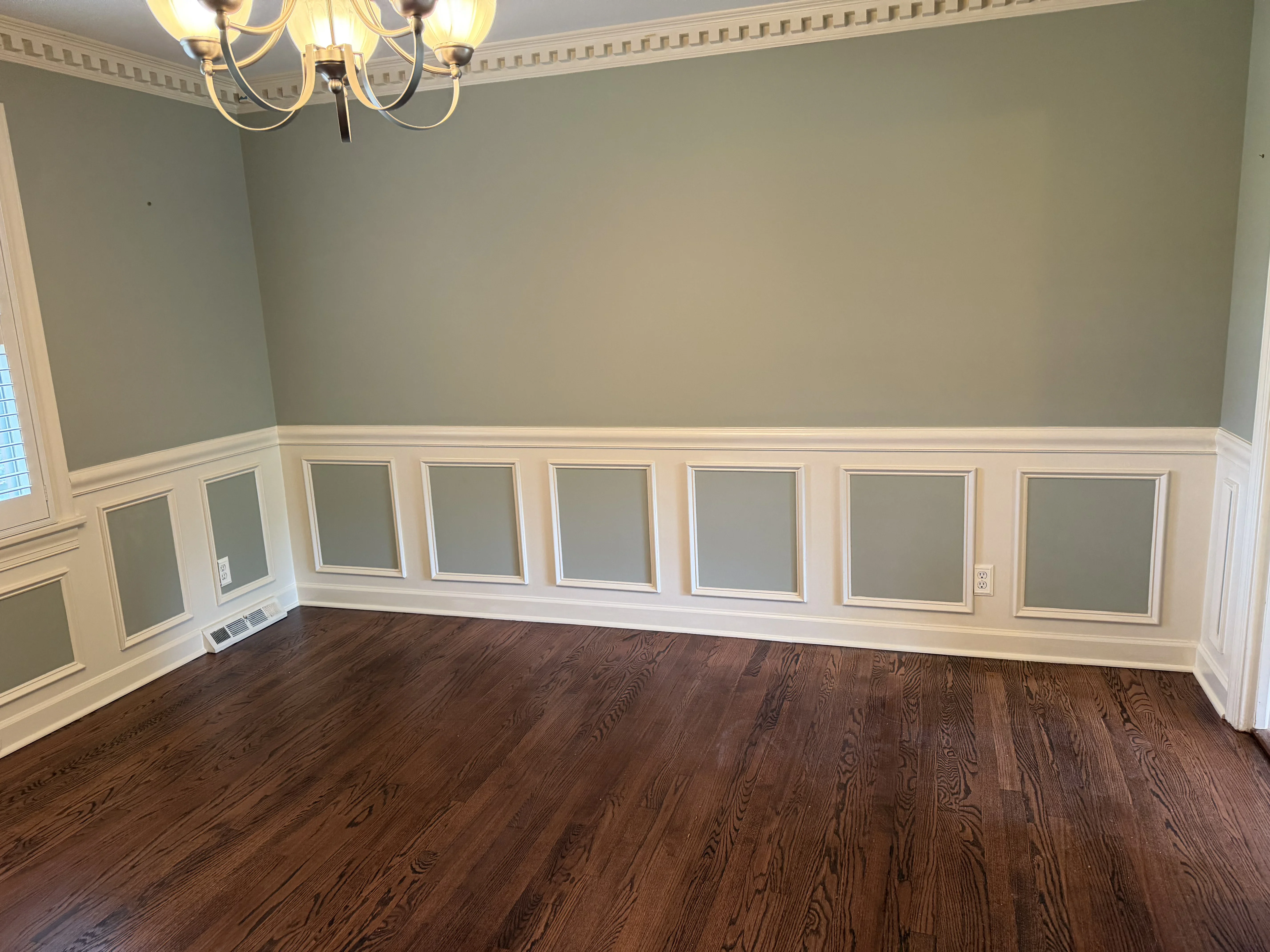 Two-tone Charlotte room with sage walls, white recessed wainscot panels, and crown molding